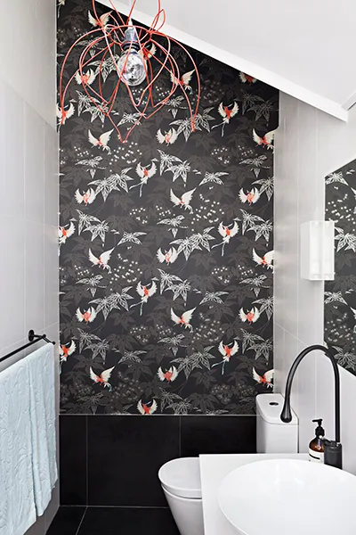 Modern bathroom designed by Pacific Designer Bathrooms with black wallpaper featuring white and red koi fish designs, a white sink and toilet, and a unique red wire light fixture.